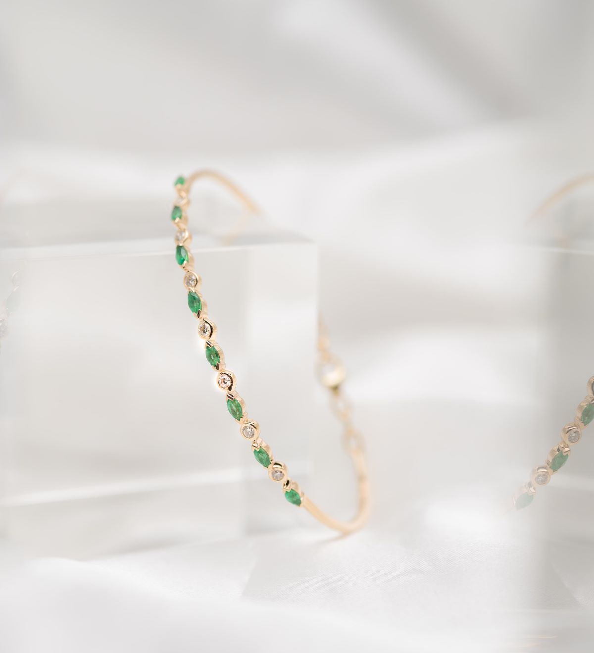 Gold and emerald green beaded earrings on a white background