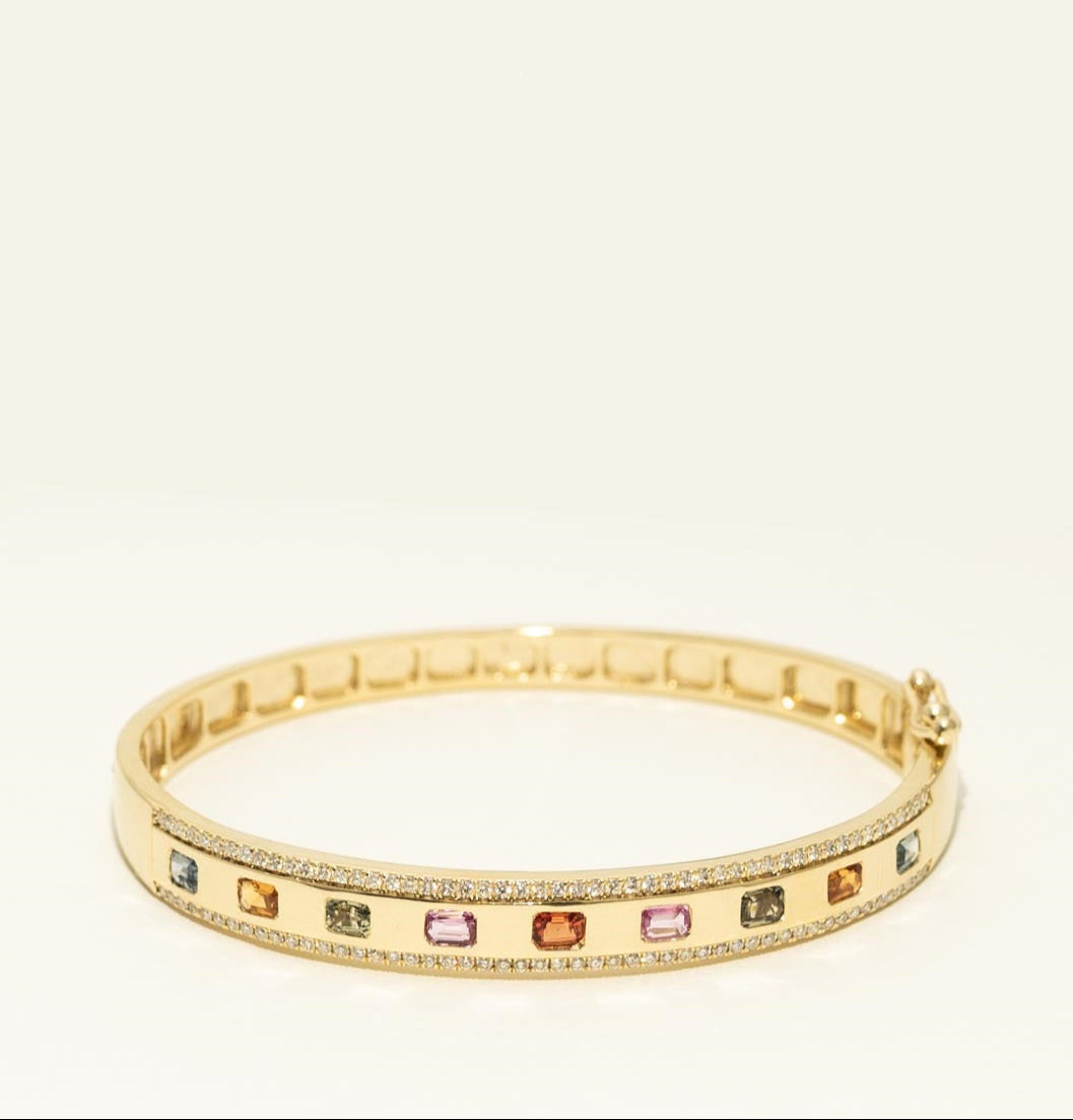 Gold bracelet with colorful gemstones on a beige background