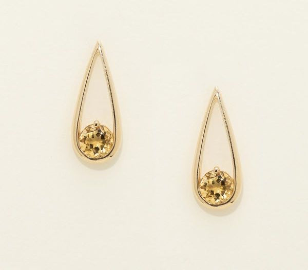 Gold teardrop earrings with embedded stones on a light beige background