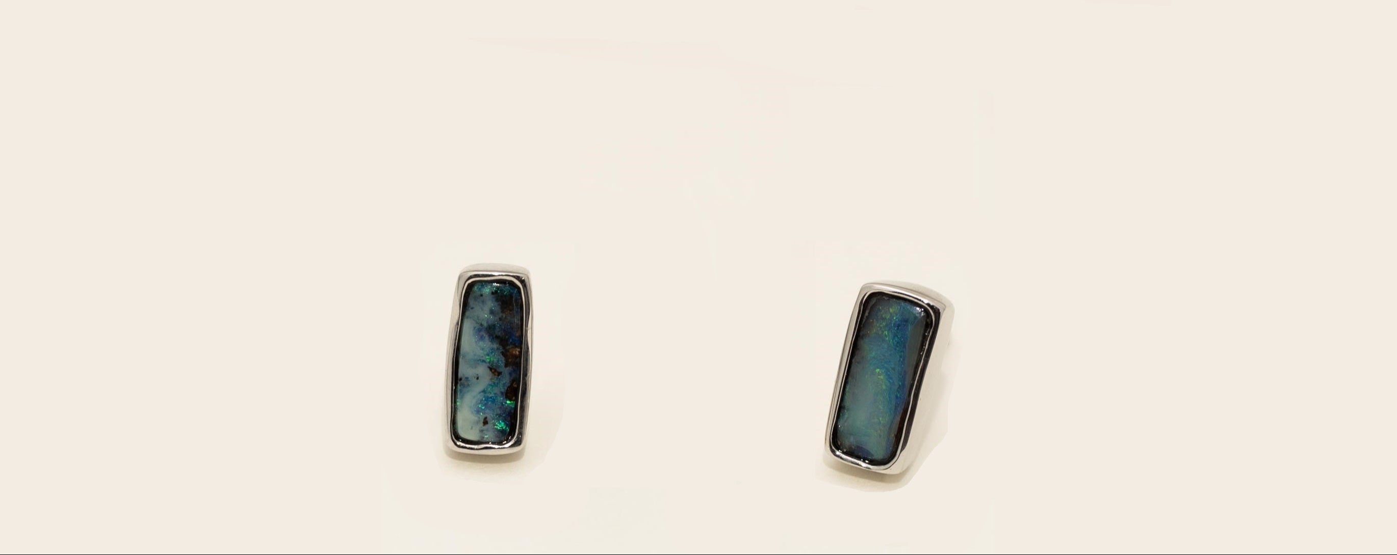 Pair of rectangular earrings with blue gemstones on a beige background