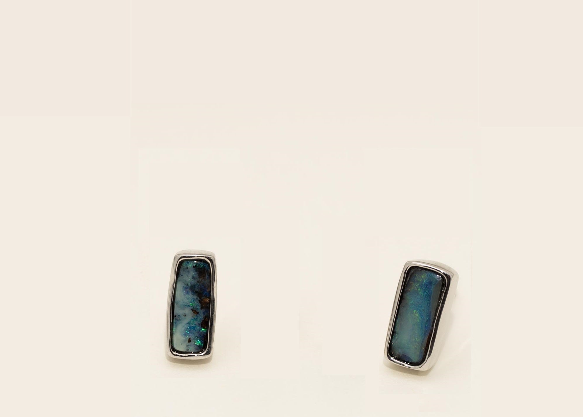 Pair of silver earrings with blue and green stone on a white background