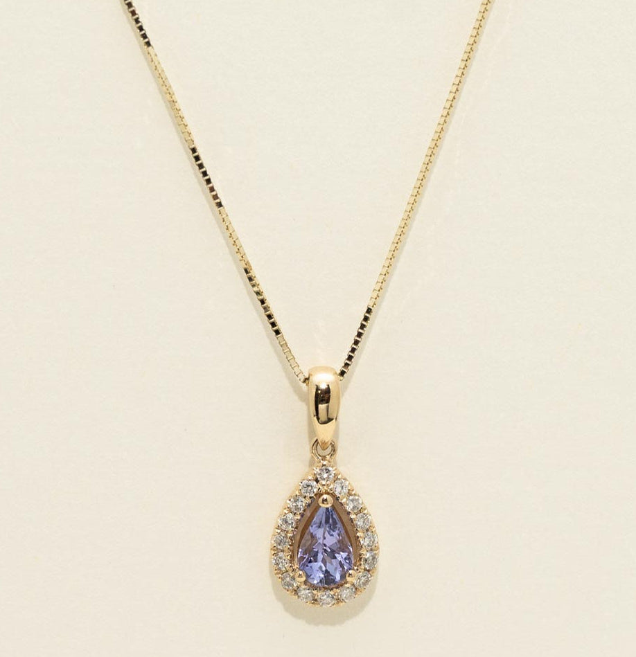 Gold necklace with a teardrop-shaped pendant on a beige background
