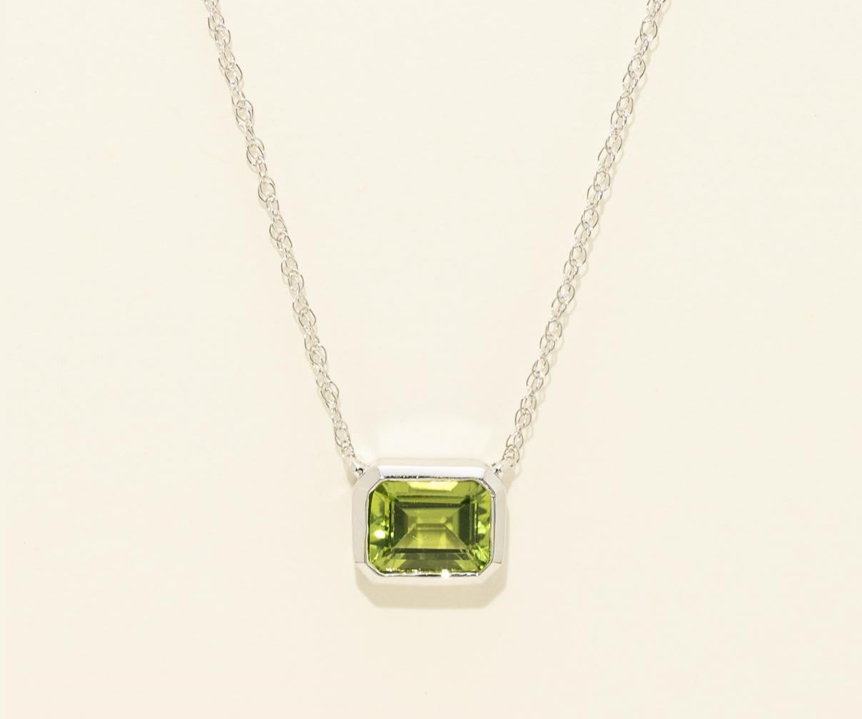 Necklace with a green gemstone pendant on a light beige background