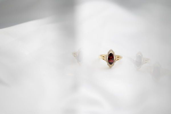 Gold ring with a red gemstone on a white background