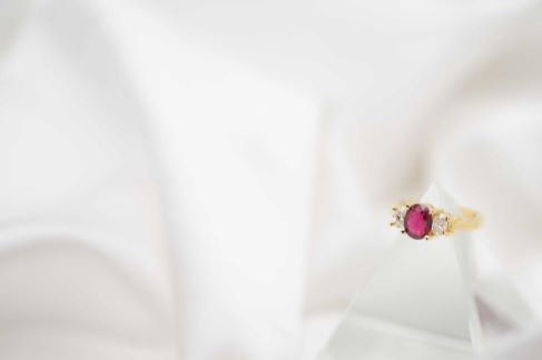 Gold ring with a red gemstone on a white fabric background