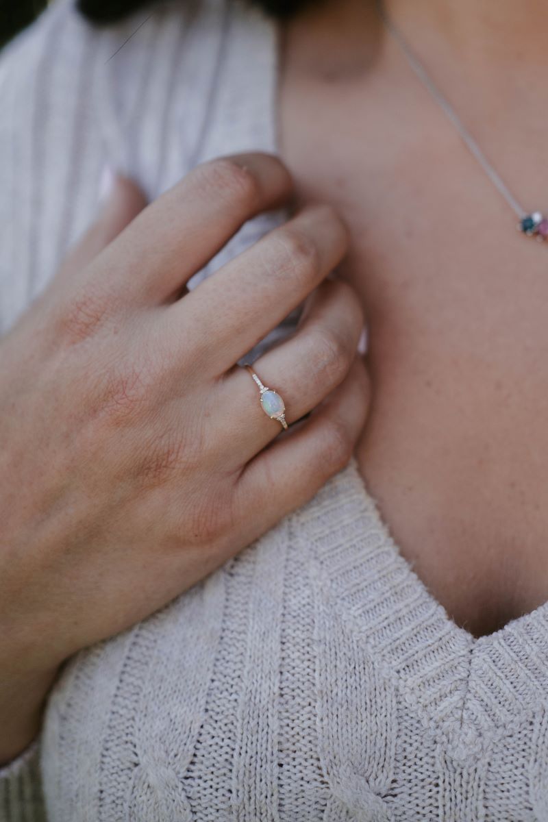 Close-up of a hand wearing a ring with a visible diamond, touching a textured surface.