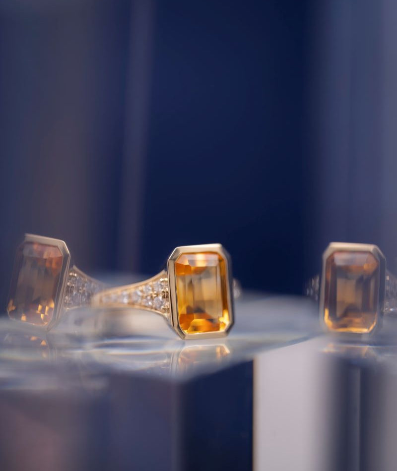 Gold ring with a rectangular orange gemstone on a blue background