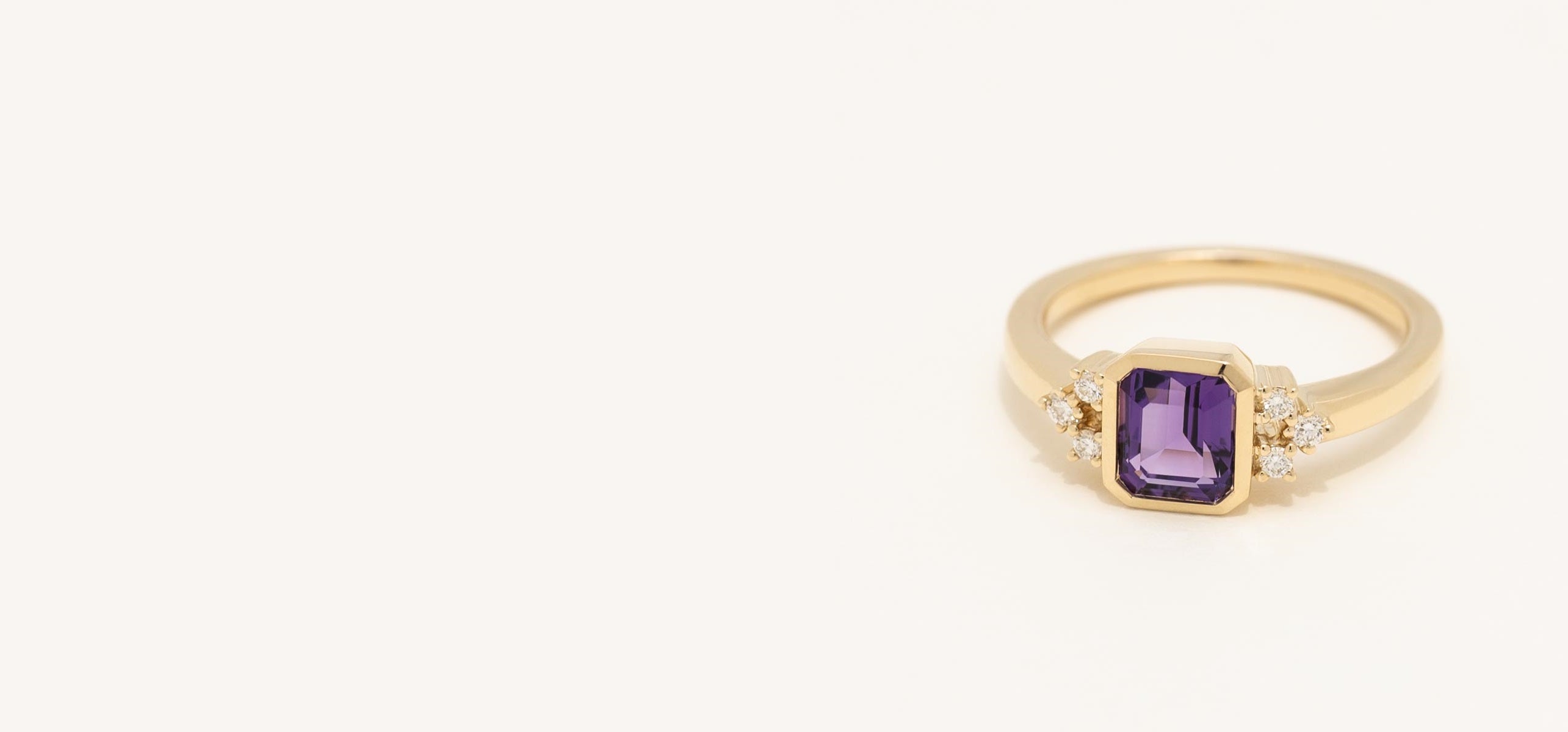 Gold ring with a purple gemstone on a white background