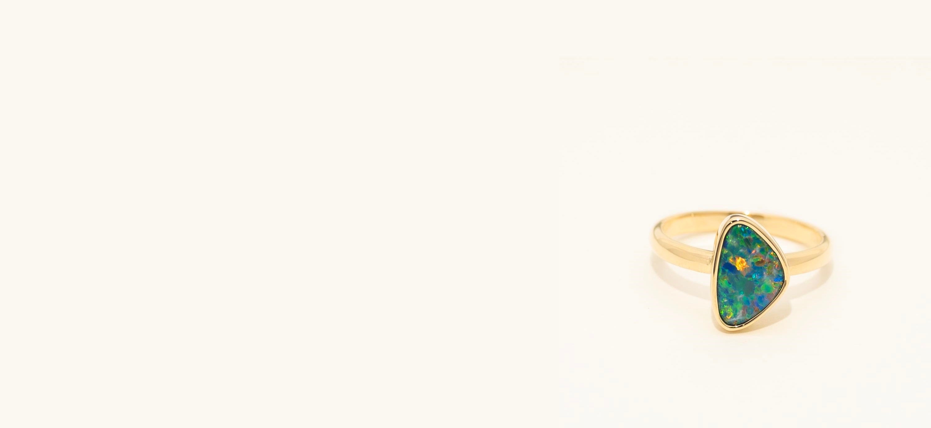 Gold ring with a green gemstone on a white background