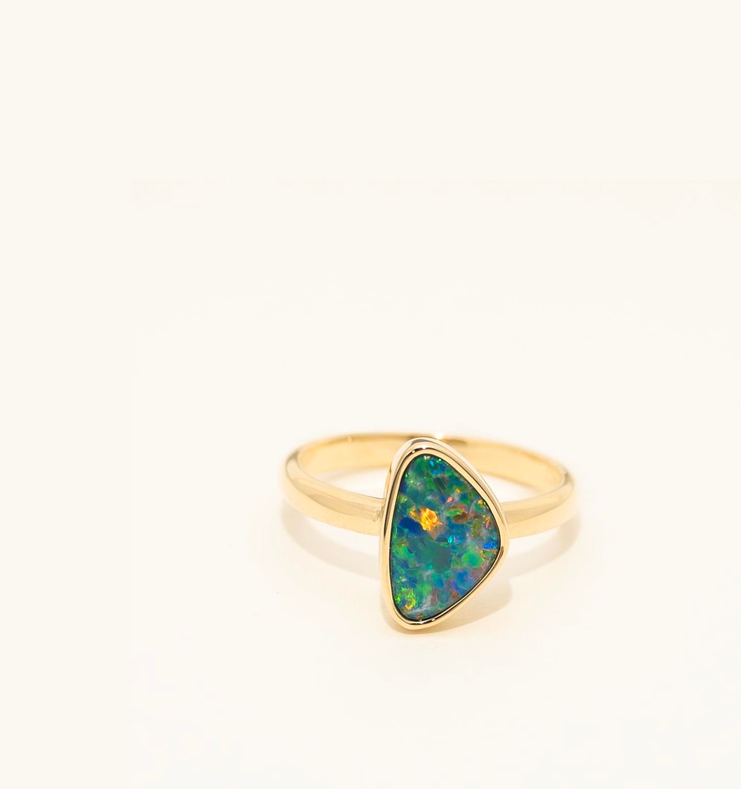 Gold ring with a green opal stone on a white background
