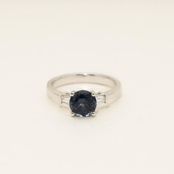 Silver ring with a dark gemstone on a light beige background
