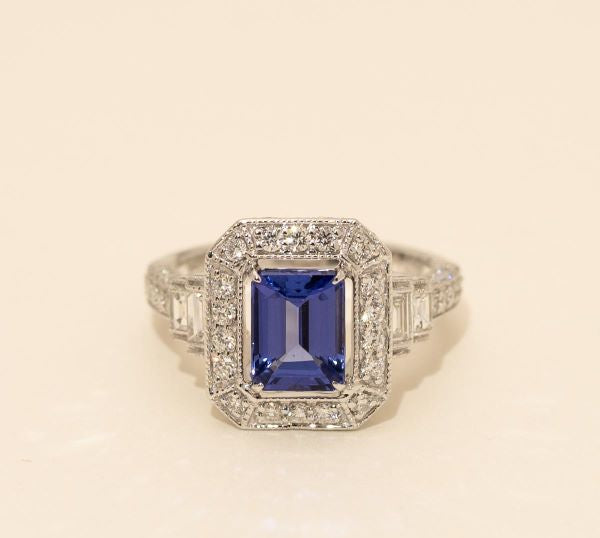 Elegant ring with a blue gemstone and diamond accents on a beige background