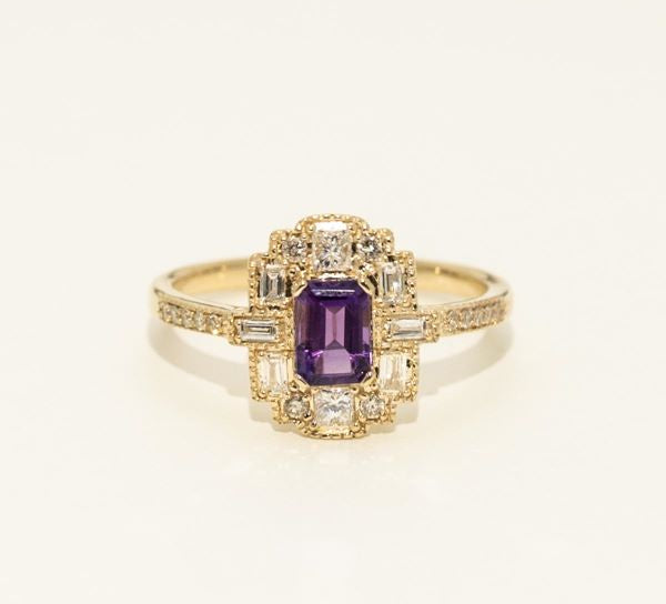 Gold ring with a purple gemstone on a white background