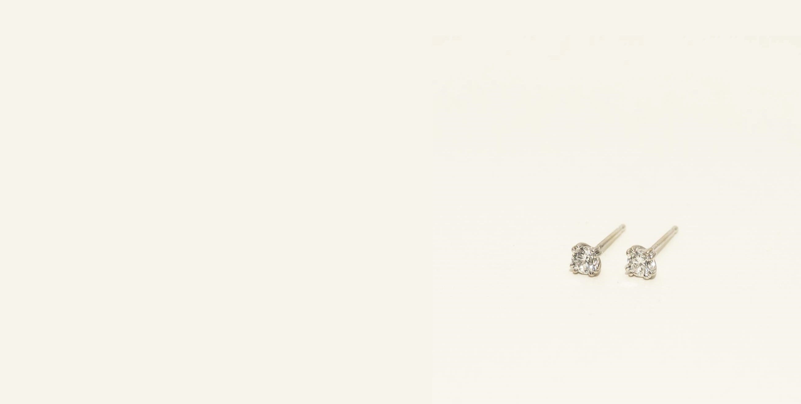 Gold earrings with small diamonds on a light beige background