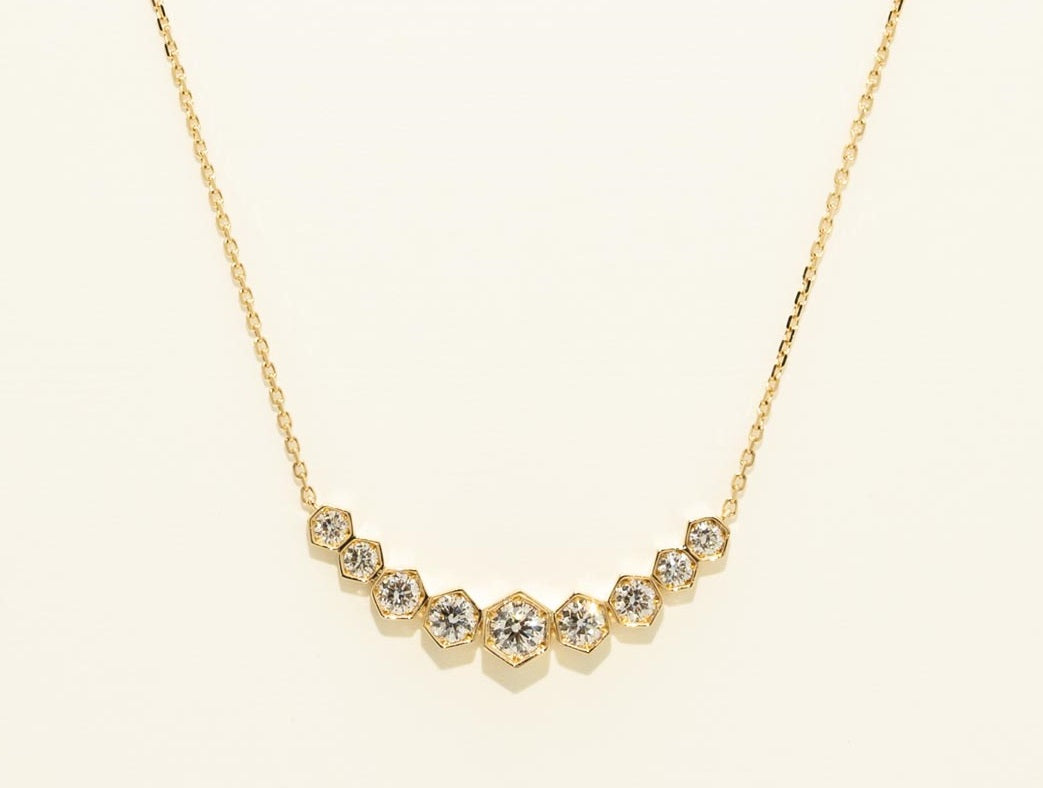 Gold necklace with hexagonal gemstones on a light beige background