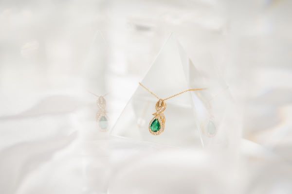 Gold necklace with a green gemstone pendant on a white background