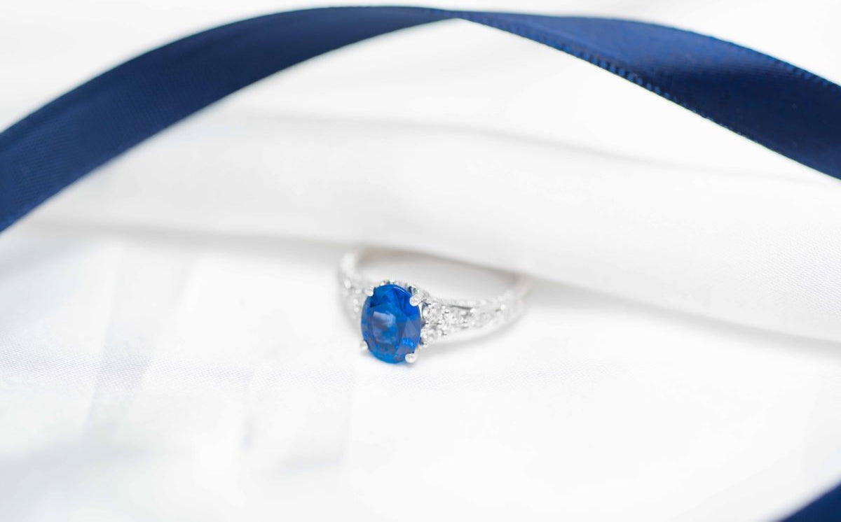 Silver ring with a blue gemstone on a white and blue striped background
