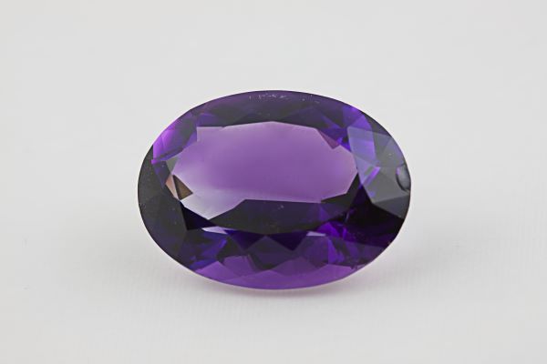 Faceted purple gemstone on a light gray background