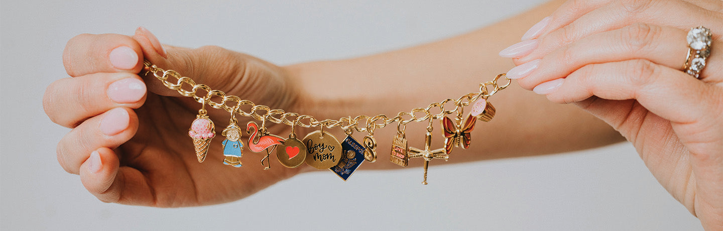 Gold bracelet with various charms held by a person against a light background