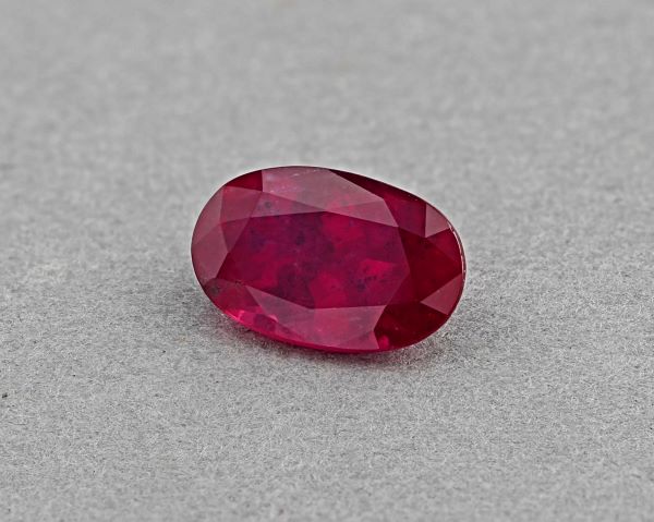 Faceted red gemstone on a gray background