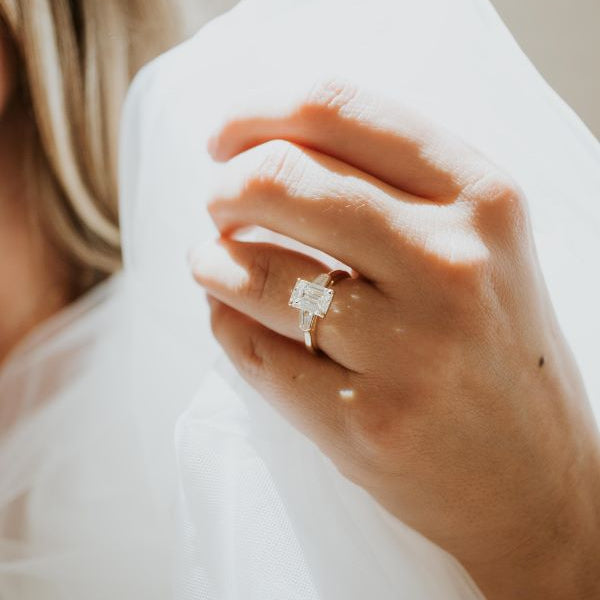 Close-up of a hand wearing an engagement ring with a soft background