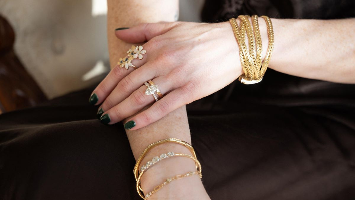 Close-up of a person's hands wearing gold jewelry on a dark background