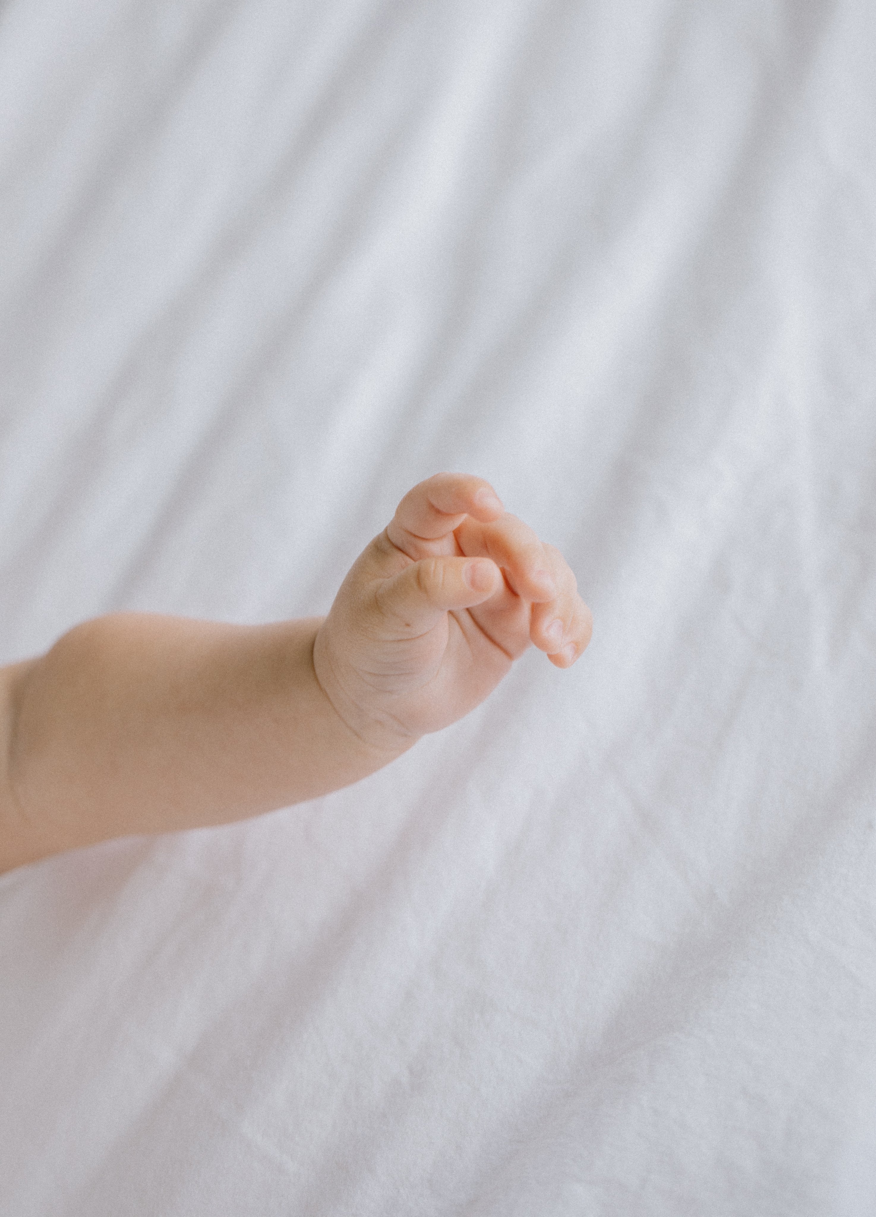 hand-of-newborn-baby-against-white-fabric.jpg