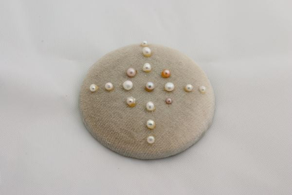 Round beige fabric patch with pearls on a light gray background